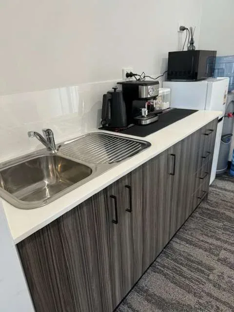 Clean office kitchenette with stainless sink and benchtop