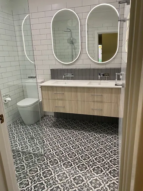 Bathroom vanity with oval mirrors and patterned tiles, freshly cleaned