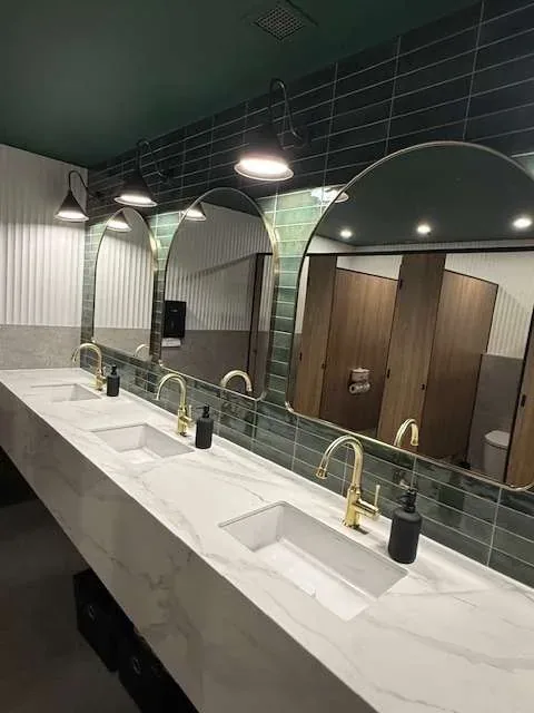 Clean double vanity and mirrors in a dark-tiled bathroom