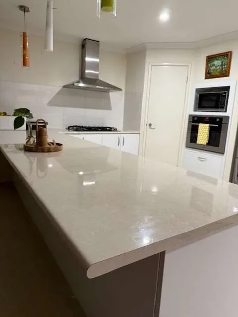 Clean white stone kitchen benchtop and splashback after a professional house clean