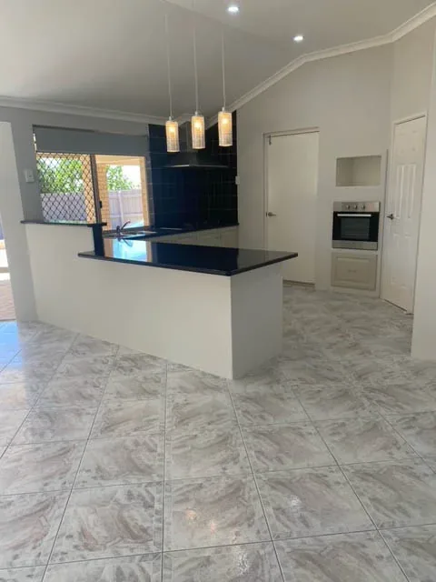 Open-plan kitchen with a clean island bench and polished tiled floor