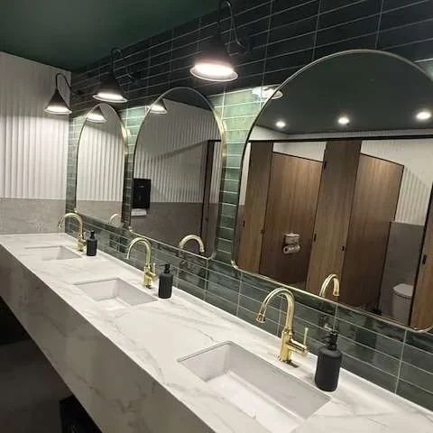A row of stone vanities and arched mirrors in a commercial washroom