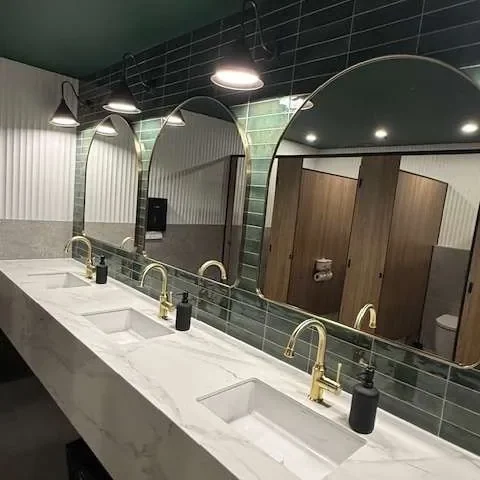 A row of stone vanities and arched mirrors in a commercial washroom