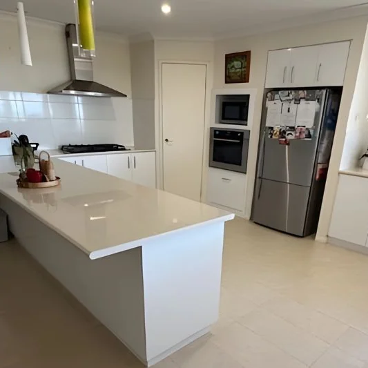 A Perth home kitchen with its stone island and benchtops wiped down after a clean