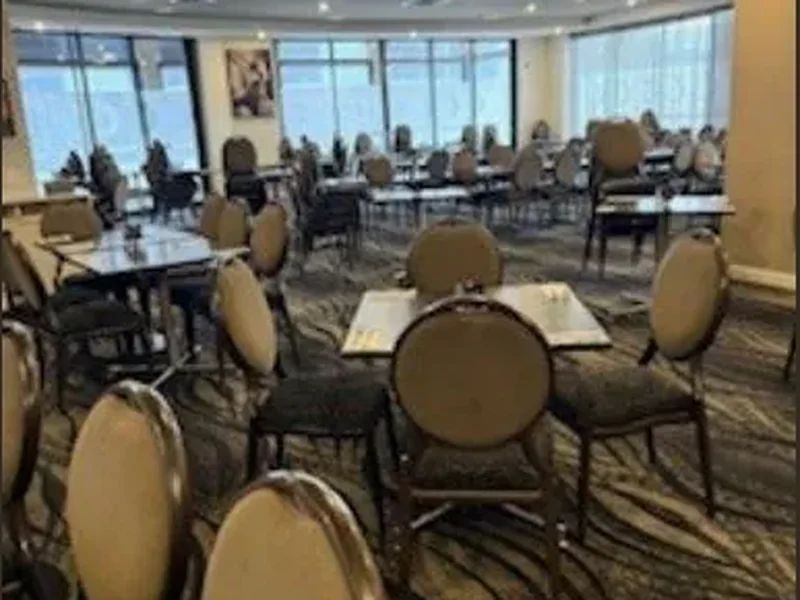 Round banquet tables and chairs reset on patterned carpet in a function room